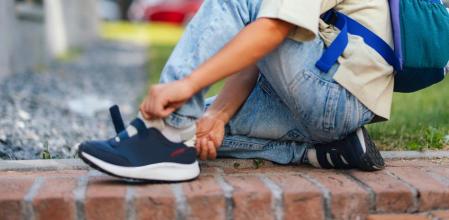 Un niño poniéndose las zapatillas para ir al colegio