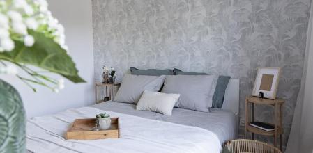 Un dormitorio con la pared del cabecero con papel pintado de flores