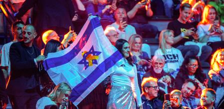 Asistentes al festival de Eurovisión en Basilea, el 15 de mayo del 2025, con una bandera de Israel con el lazo amarillo por los rehenes&nbsp;&nbsp;