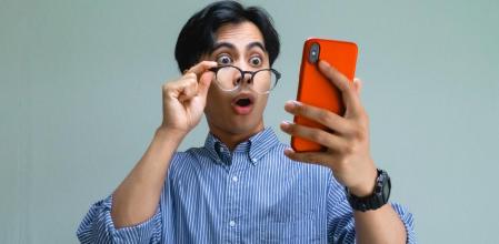 Un señor se sorprende al mirar la pantalla de su teléfono móvil
