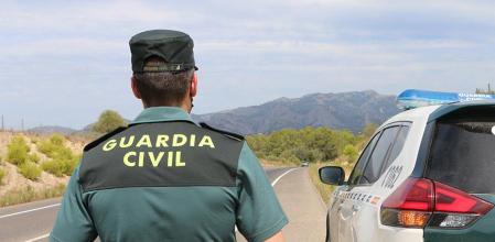 Un agente de la Guardia Civil junto a un vehículo en una carretera. (Foto de archivo).
