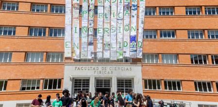 Alumnos y profesores cuelgan un mural de la fachada de la Facultad de Físicas de la Universidad Complutense de Madrid.