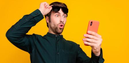 Un hombre sorprendido mirando el móvil