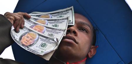  Una persona sostiene billetes con la imagen del presidente de los Estados Unidos, Donald Trump, durante la Marcha Global por el Clima, en protesta por la defensa de los bosques, los derechos territoriales indígenas y la responsabilidad climática global este sábado, en Belém (Brasil). EFE/Andre Borges