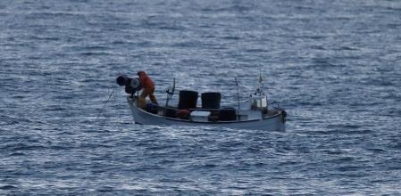 Pescador faenando con su barca frente a la playa de La Fosca de Palamós.