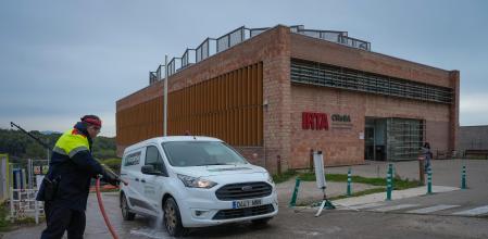 Un agente rocía las ruedas de un vehículo para desinfectarlo a la salida de las instalaciones del IRTA-CReSA, en Bellaterra