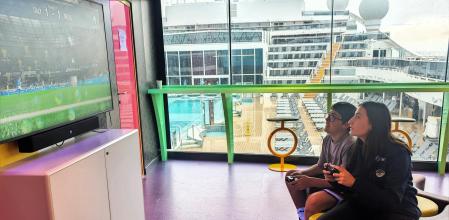 La monitora Ilenia con uno de los jóvenes pasajeros del 'MSC World Europa' en plena partida de futbol digital&nbsp;