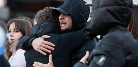 People hug near a makeshift memorial outside the