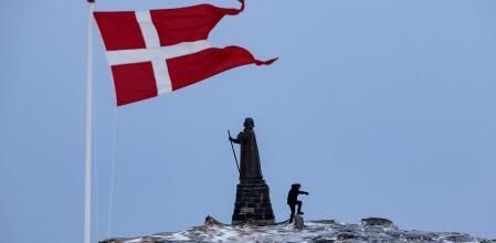 Un hombre camina mientras la bandera danesa ondea junto a la estatua de Hans Egede antes de las elecciones generales del 11 de marzo en Nuuk, Groenlandia