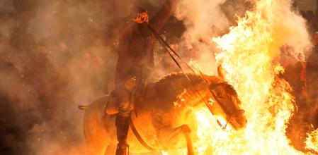 Un jinete cabalga a través de una hoguera durante la celebración anual de las “Luminarias” en la víspera del día de San Antonio, el santo patrón de los animales de España&nbsp;