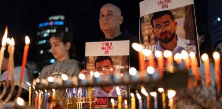 Israelíes encienden la octava vela de Janucá en la Plaza de los Rehenes con pancartas con el rostro de Ran Gvili en Tel Aviv, el pasado 21 de diciembre&nbsp;