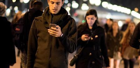 Peatones cruzando la calle mientras miran el móvil