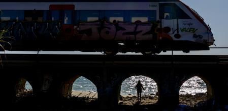 Un tren de la línea R1 circula junto al mar por encima de uno de los puentes que dan salida a las numerosas rieras de la zona