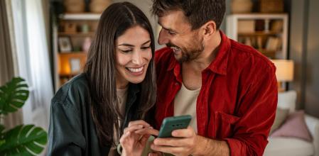 Una pareja sorprendida y feliz con lo que ve en el móvil