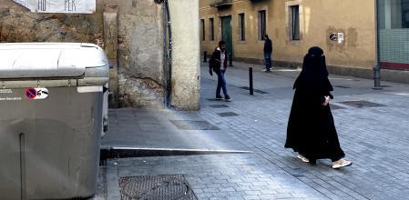 Una mujer con burka camina por las calles del Raval