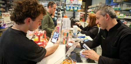 Un joven muestra al farmacéutico un vídeo de TikTok con el nombre del medicamento (finasterida) que quiere comprar