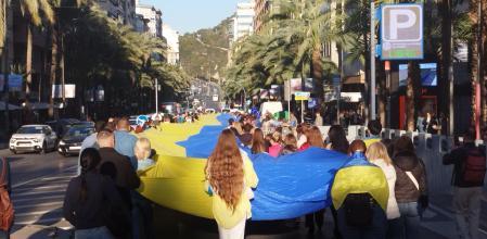 Los ucranianos de Alicante recorren la ciudad portando una inmensa bandera de su país el 24 de febrero de 2024