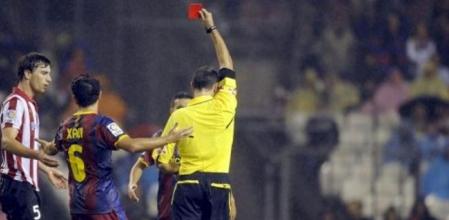 El árbitro del colegio valenciano, Mateu Lahoz, muestra la cartulina roja al defensa del Athletic de Bilbao, Fernando Amorebieta (i), tras una entrada sobre el centrocampista del FC Barcelona, Andrés Iniesta (d), durante el partido correspondiente a la quinta jornada de la Liga en Primera División disputado en el estadio de San Mamés, en Bilbao