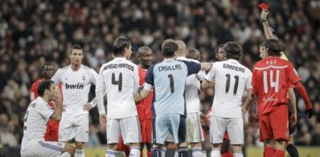 El árbitro del encuentro, Carlos Clos Gómez (d), muestra la tarjeta roja al defensa portugués del Real Madrid Ricardo Carvalho (i) durante el partido correspondiente a la decimosexta jornada del Campeonato Nacional de Liga de Primera División que enfrenta esta noche al conjunto blanco con el Sevilla CF en el estadio Santiago Bernabéu