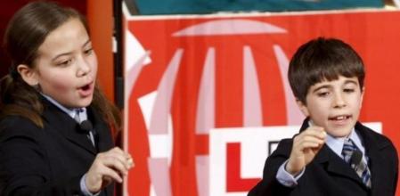 Los niños del colegio de San Ildefonso Eduardo Escobar y Alejandra Alves muestran el número 69.069 que ha sido premiado con uno de los quintos premios, dotado con 50.000 euros la serie, del sorteo de la lotería de Navidad