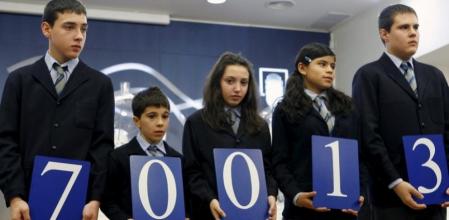 Los niños de San Ildefonso muestran el primer premio del sorteo de la lotería de 'El Niño'