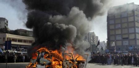 La multitud en Trípoli observa como arde un vehículo de la cadena de televisión Al Jazeera, quemado por los manifestantes
