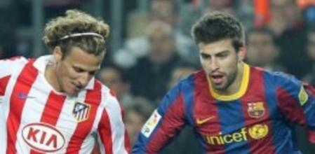 El defensa del FC Barcelona Gerard Piqué disputa un balón con el delantero uruguayo Diego Forlán, del Atlético de Madrid