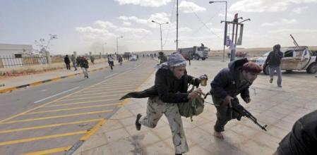 Rebeldes libios huyen mientras las fuerzas leales al régimen del líder libio Gadafi bombardean sus posiciones en Ras Lanuf, la terminal petrolera libia en poder de los milicianos