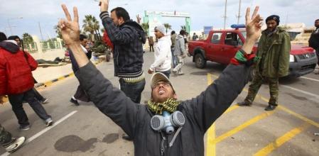 Un rebelde alza los brazos al cielo tras haber salido indemne de un bombardeo del Ejército libio