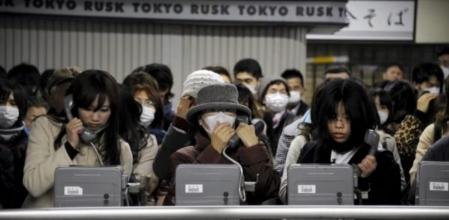 Una multitud de personas esperan para poder utilizar las cabinas de teléfono mientras la mayor parte de los móviles continúan sin cobertura tras el terremoto
