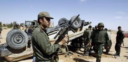 Soldados tunecino junto a un vehículo volcado que fue utilizado por las tropas leales al líder libio Muamar al Gadafi en el último combate con los rebeldes en el pueblo de Dhiba
