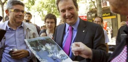 Un vecino muestra al alcalde de Barcelona y candidato a la reelección, Jordi Hereu, una fotografía del expresidente del Gobierno, José María Aznar, y del candidato a la Alcaldía de la ciudad condal por CiU, Xavier Trias,