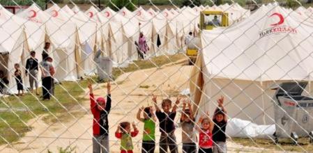 Un grupo de niñas y niños refugiados sirios hacen el símbolo de la victoria en Boynuyogun, donde está instalado el campamento de la Media Luna turca.