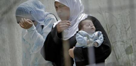 Una refugiada siria en el complejo de Yayladagi, al lado de la frontera siria, sostiene un bebé y camina junto a otra compatriota.