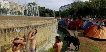 Jóvenes acampados en la plaza Catalunya se bañan en la fuente.