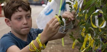 Un niño cuelga una pulsera como reivindicación para la liberación del soldado Gilad Shalit en Mitzpe Hila.