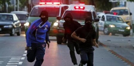 Tres encapuchados huyen de la policía tras levantar una barricada.