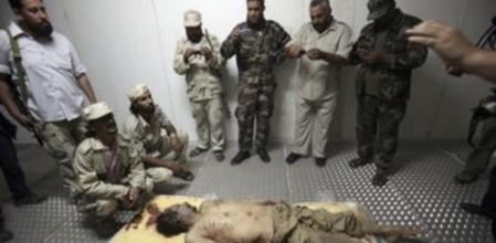 El cadáver del dictador Muamar el Gadafi es custodiado por unos combatientes rebeldes en unas instalaciones refrigeradas en Misrata. Todos quieren hacerse una foto.