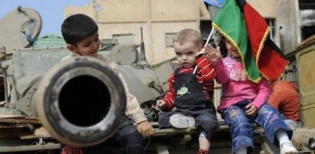 Niños libios sentados encima de un tanque sostienen una bandera de Libia, en Misrata