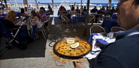 Un camarero se dispone a servir una paella en un chiringuito de playa en Barcelona