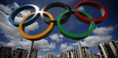 Los cinco aros olímpicos y, al fondo, algunos de los edificios donde se alojan los atletas