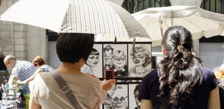 Unas turistas se protegen del sol con paraguas en la Rambla de Barcelona