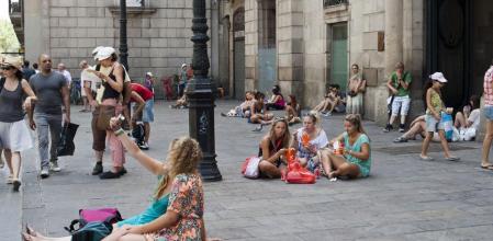 Turistas descansan o reponen fuerzas comiendo un tentempié frente al palacio de la Virreina, en la Rambla