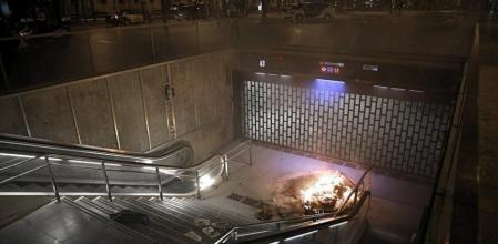 Una hoguera arde en la entrada de una boca de metro del centro de Barcelona durante la jornada de huelga general