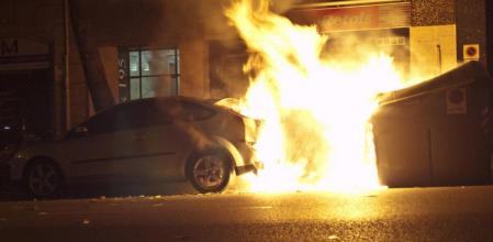 Fotografía tomada en la calle Nápols de Barcelona alrededor de las 23:00h el 14-N (Huelga general): arden un contenedor de basura y un coche estacionado