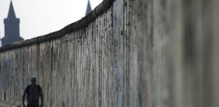 Un turista pasea a lo largo de los restos conservados del muro de Berlín junto al río Spree.