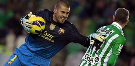 El portero del Barcelona, Víctor Valdés (i), atrapa la pelota ante la presión del centrocampista del Betis, Salva Sevilla (d), durante el partido correspondiente a la decimoquinta jornada de la Liga de Primera División disputado en el estadio Benito Villamarín en Sevilla. EFE/Paco Puentes