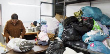 Una voluntaria de Cáritas repasa la ropa que reciben para mirar que esté en buenas condiciones