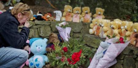 Una vecina se arrodilla frente a 26 ositos de peluche que recuerdan a las víctimas de la masacre en una escuela de Newtown, en Connecticut