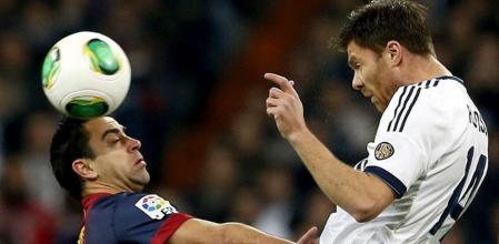 El centrocampista del Real Madrid Xabi Alonso (d) remata de cabeza ante el mediocentro del F.C. Barcelona Xavi Hernández durante el partido de ida de las semifinales de la Copa del Rey disputado esta noche en el estadio Santiago Bernabéu.